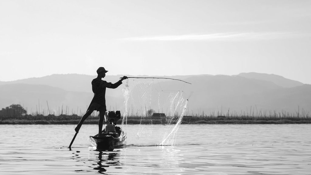 Silhouette of a fisherman casting a net on Inle Lake, Myanmar, in stunning black and white.